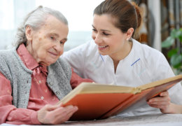 Caregiver and old woman reading a book